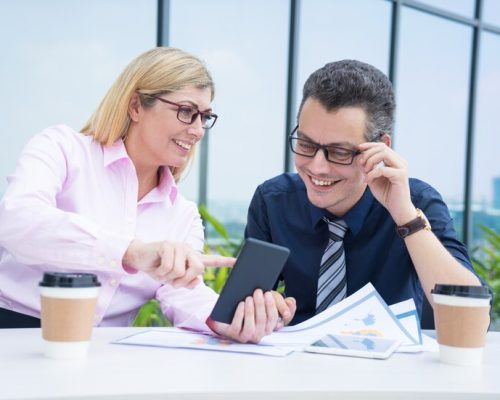 two-smiling-business-colleagues-using-phone-cafe-break_1262-12579